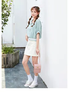 Pink rectangular crossbody bag with gold buckle styled with a green lace-trim shirt