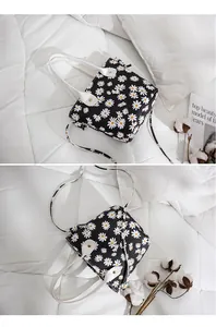 Détail du sac seau à motif marguerites avec poignées blanches et bandoulière réglable