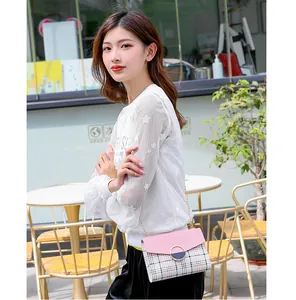 Close-up of pink leather crossbody bag with plaid pattern and gold chain strap in cafe