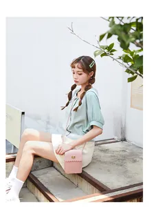 Close-up of pink crossbody phone bag with scalloped edge and golden heart lock