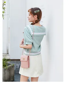 Detail of a pink crossbody bag with scalloped edges and gold twist lock on a model