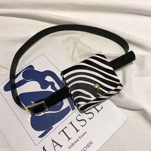 Stilvolle Zebra-Mini-Gürteltasche mit goldener Schnalle auf künstlerischem Stoffhintergrund