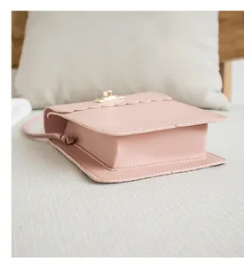 Detail of pink faux leather handbag with scalloped edges and gold twist-lock closure