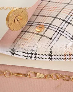 Detail of the golden magnetic clasp and plaid textured surface on the chain shoulder bag