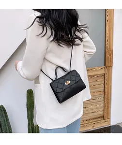 Quilted black crossbody bag with gold oval twist lock shown on model wearing white suit
