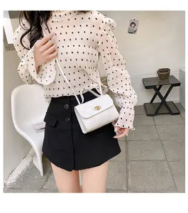 Detail of white quilted square crossbody bag with gold oval twist lock on female model
