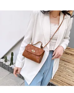 Close-up of brown quilted crossbody bag with gold metal clasp on a stylish model