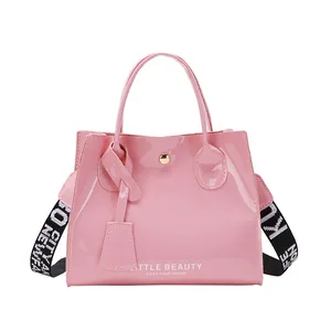 Sac à main en cuir verni rose avec logo blanc et bandoulière en sangle rayée