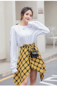 Close-up of a stylish woman's street style outfit with plaid skirt and micro jelly bag