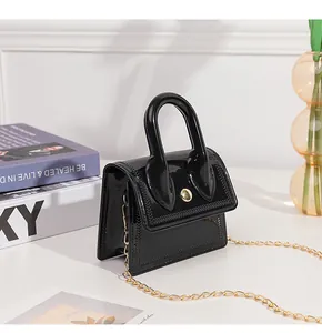 Close-up of black jelly bag with glossy PVC finish, gold chain and V-shaped stitching