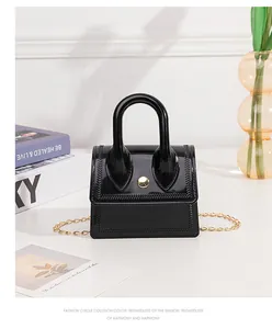 Detail of black jelly mini bag with golden buckle and chevron stitching on white surface