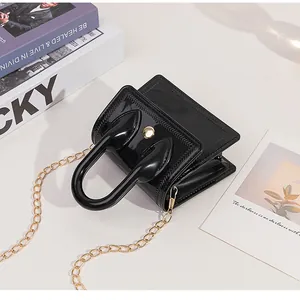 Close-up of black glossy mini PVC bag with gold button and unique handset-style handle