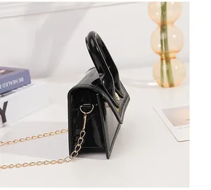 Side view of black patent leather mini handbag with gold chain strap and thick handle