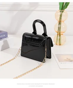 Close-up of black glossy mini jelly bag with gold chain strap and fine stitching