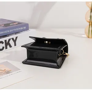 Detail view of mini black patent leather jelly bag with gold magnetic snap and chain
