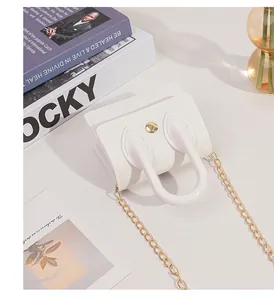 Detailed close-up of a white mini jelly bag with gold chain strap and snap closure