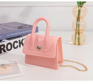 Detailed view of mini pink jelly handbag with gold chain strap on a white table