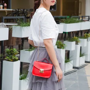 Women's bright red small crossbody bag with gold chain strap and lock buckle details