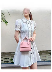 Petit sac carré élégant en similicuir rose avec chaîne porté par un mannequin en robe