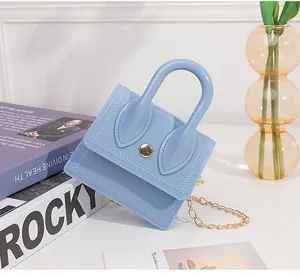 Detail of light blue mini jelly bag with arrow embossing and gold buckle on books