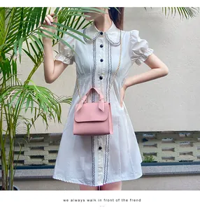 Petit sac carré rose avec poignée en ruban de soie et chaîne dorée sur robe blanche