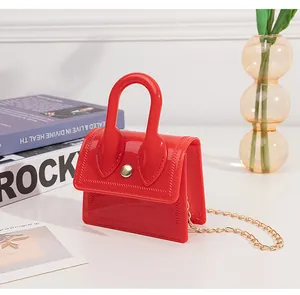 Detail of red mini jelly handbag featuring gold chain strap and metallic buckle closure