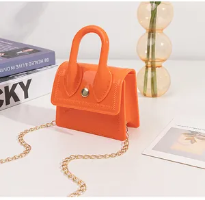 Detailed view of orange mini jelly PVC handbag featuring gold chain and snap closure