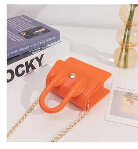 Detail of mini orange jelly bag with gold chain strap and textured chevron flap
