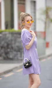 Détail du mini sac matelassé noir avec poignée en perles et chaîne dorée sur robe