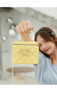 Detail of yellow jelly bag with diamond quilting, pearl handle and gold heart logo