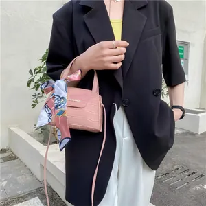 Pink faux crocodile leather crossbody bag with silk scarf handle on outdoor female model
