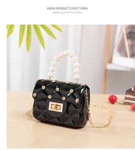 Détail du mini sac gelée noir avec texture matelassée, poignée perle et chaîne dorée