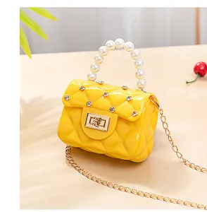 Détail du sac jelly jaune avec texture matelassée, poignée perle et chaîne diamantée