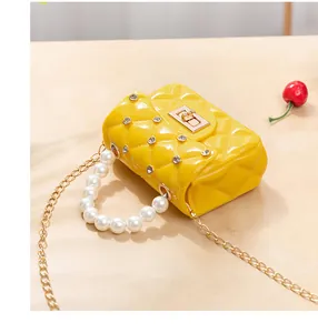Détail du mini sac gelée jaune avec motif losanges, poignée en perles et chaîne dorée