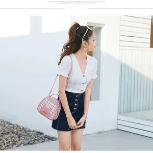 Detail of pink plaid shoulder bag with cat ear pocket and letter tag in street style