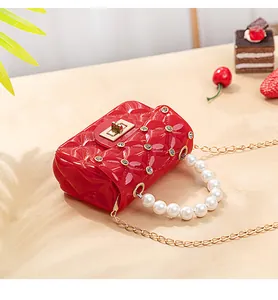 Détail du sac jelly rouge matelassé avec perles, chaîne diamant et fermoir doré