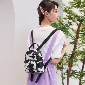 Mini backpack for women featuring cow print and adjustable black straps on a casual model