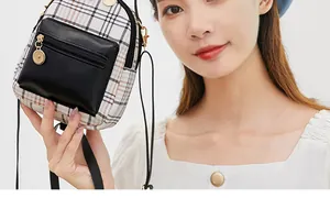 Close-up of mini plaid crossbody bag with black zipper pocket and gold metal hardware