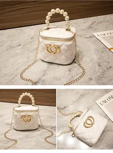 Dettaglio mini borsa a secchiello trapuntata bianca con manico di perle e cuore dorato