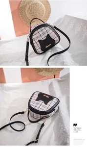 Detail of a chic cat-themed crossbody bag with beige plaid pattern and gold logo