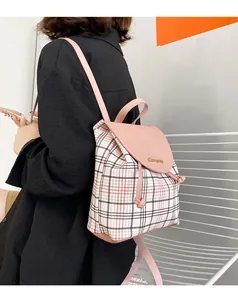 Detalle de la mochila de cuadros rosa y blanco con logotipo de metal dorado en la solapa