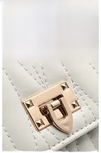 Detailed macro view of white V-quilted leather with a gold rectangular twist lock