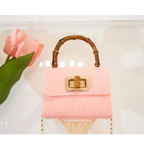 Dettaglio della mini borsa rosa con trama a coccodrillo e iconico manico in bambù