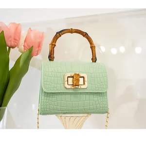 Dettaglio mini borsa verde menta stampa coccodrillo con manico in bambù e chiusura oro