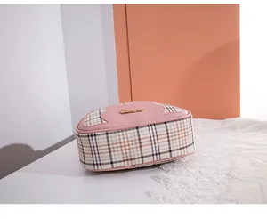 Detail view of pink PU leather and beige plaid stitching with golden metal logo