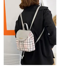 Detalle de una mini mochila de cuadros con solapa de cuero y cordón llevada por una modelo