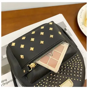 Detail of black leather bag with gold rivets and a front zipper holding cosmetics