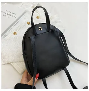 Detail view of mini black PU leather backpack back with straps and gold headphone port
