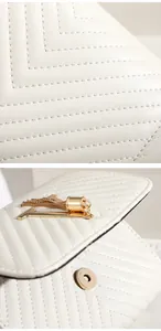 Detail of white quilted leather handbag with V-shaped stitching and gold tassel chain