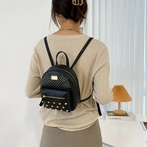 Chic black mini backpack for women with gold rivets and adjustable straps on a model